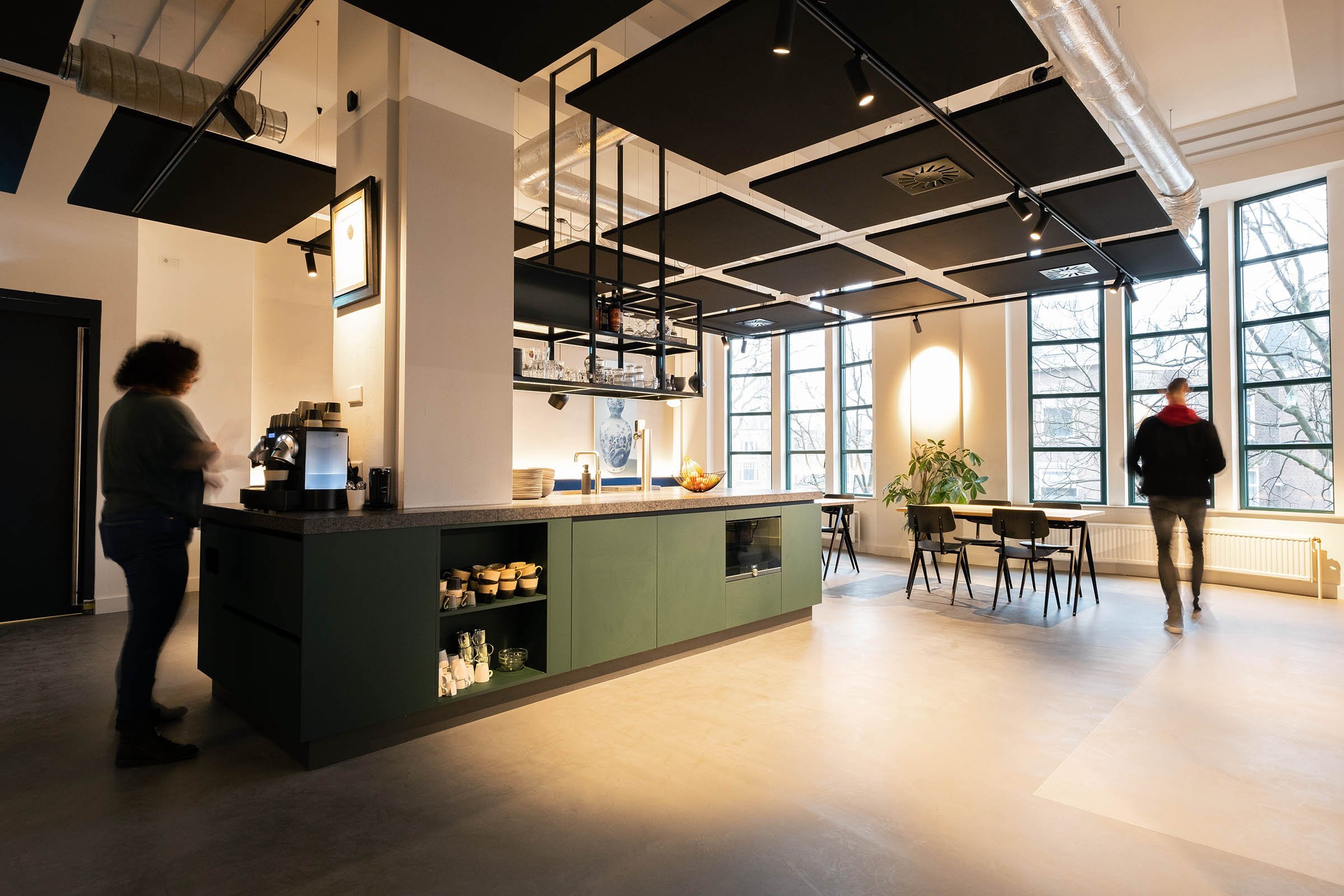 Industrieel kantoor in Den Haag met open plafond en zwarte akoestische panelen en rail spots met groene bar