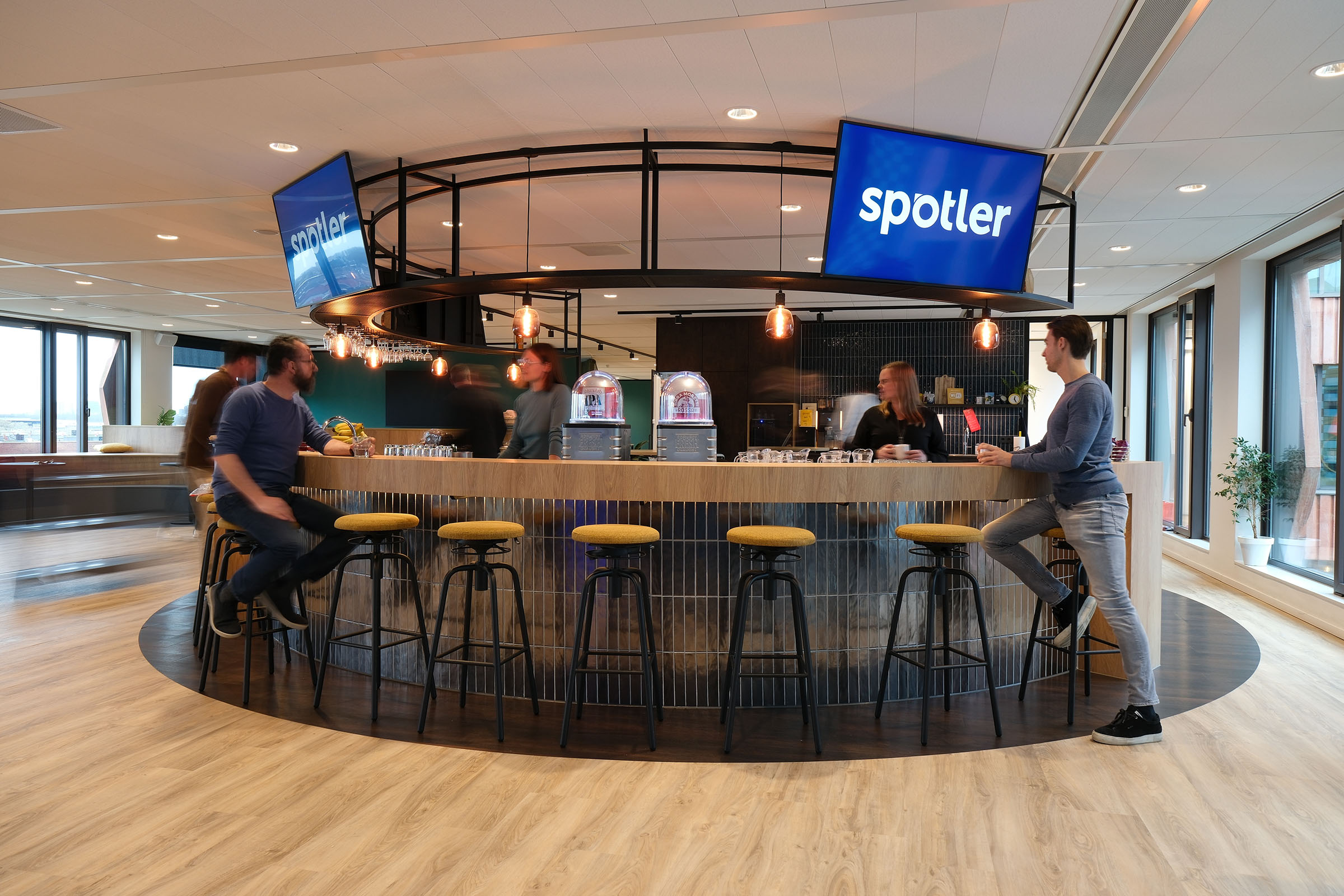 Ronde bar met stoere krukken in modern kantoor met sportsbar vibes