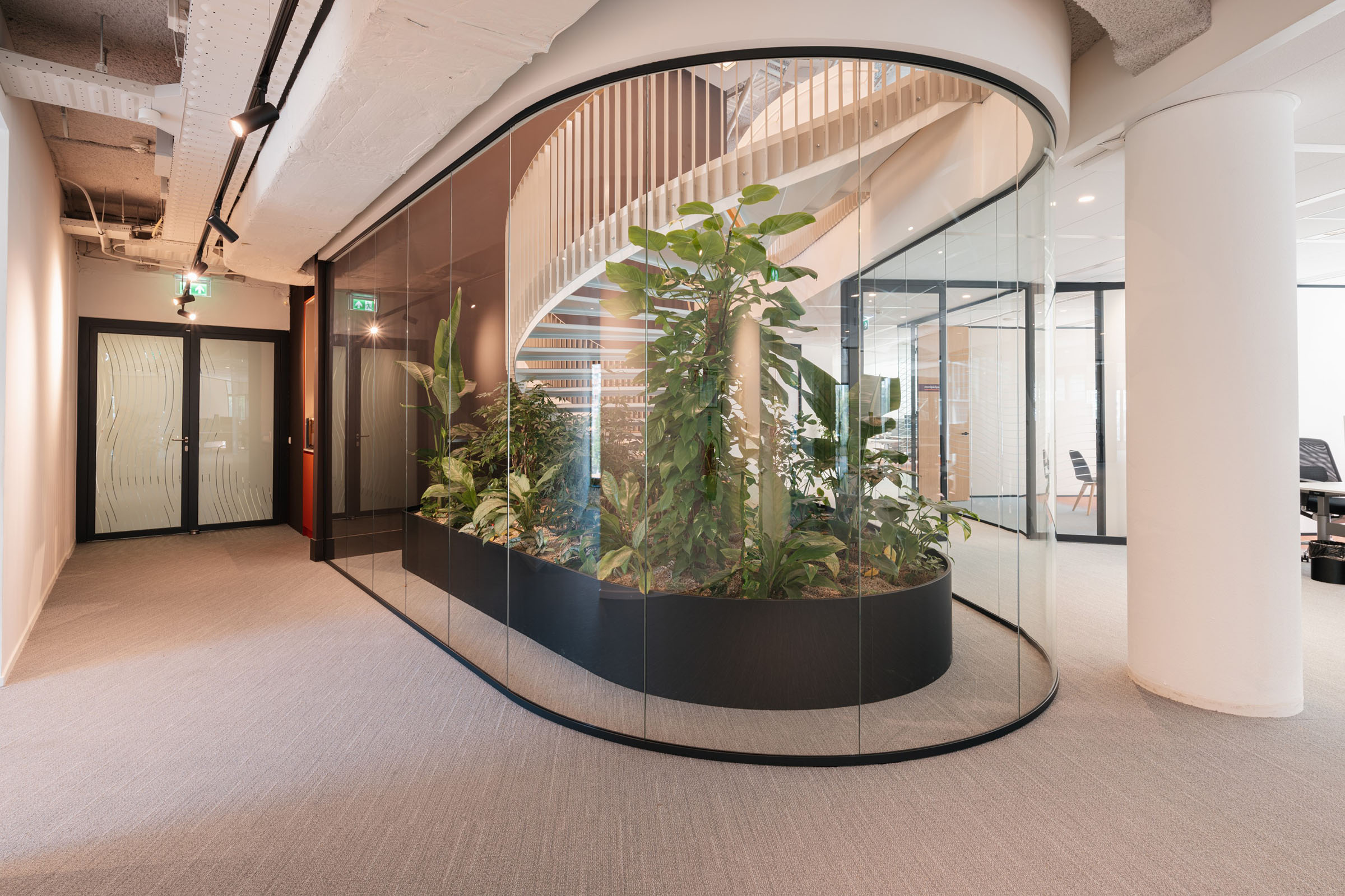 Ronde organische vormen en veel planten met centrale spiltrap in modern kantoor